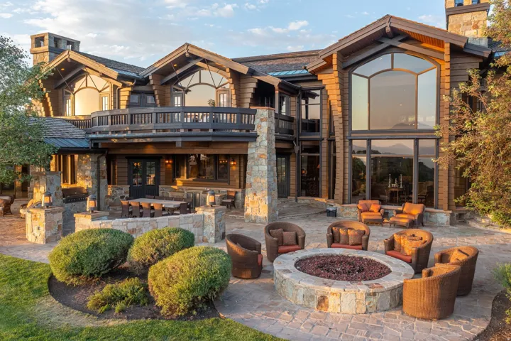 Expansive stone paver patio featuring a built-in stone fire pit, generous outdoor living space, and an additional covered dining area
