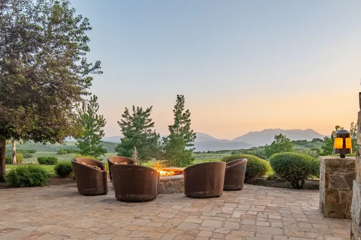 Stone patio featuring a built-in fire pit, stone accent column with a sconce, and distant mountain scenery