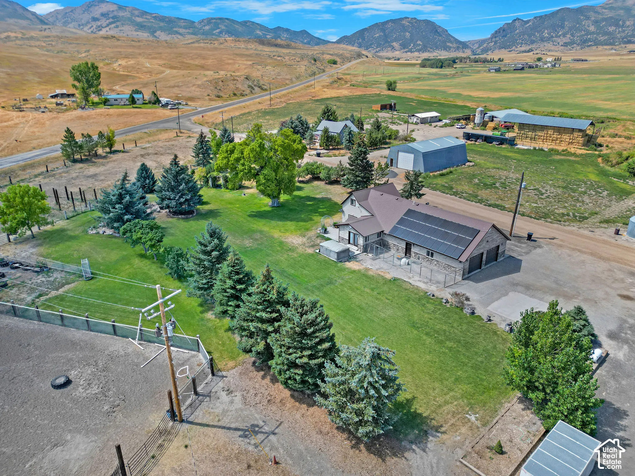 Expansive property featuring a residence with solar panels and an attached garage, a large metal barn, and additional outbuildings