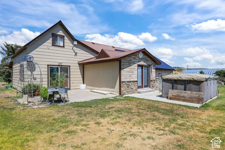 Rear exterior featuring a stone and siding facade, a metal roof, and a concrete patio