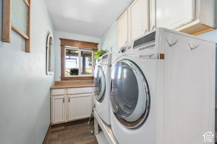 Dedicated laundry area featuring wood-finish flooring and a light-toned countertop with integrated cabinetry