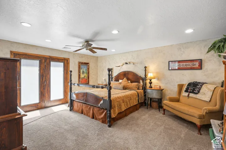 Primary room featuring a ceiling fan, recessed lighting, double French doors, textured wall finishes, and carpeting