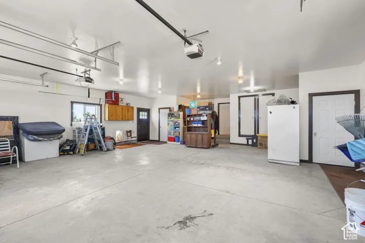 Spacious garage featuring a concrete floor, multiple entryways, built-in cabinetry, and overhead garage door tracks