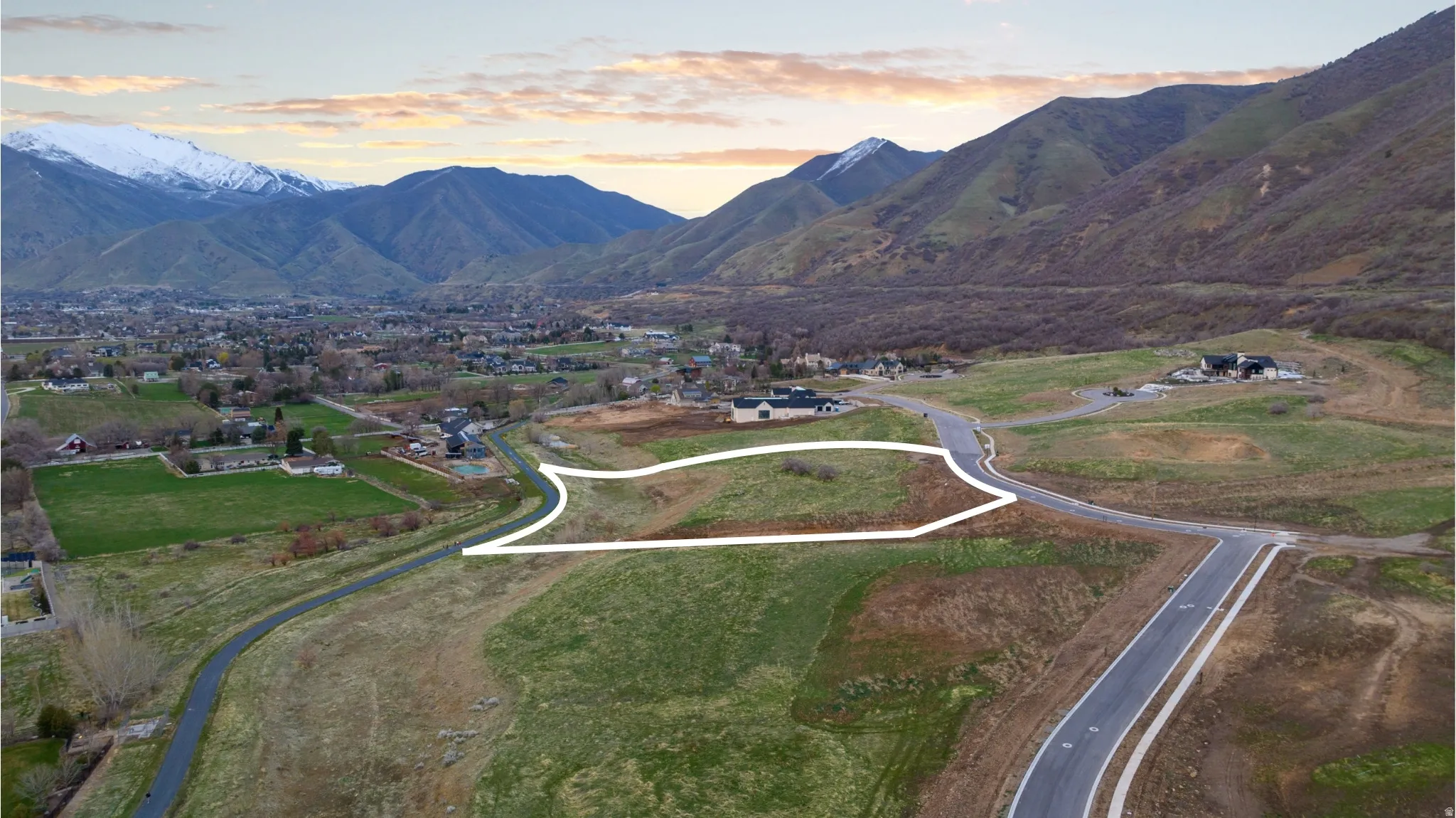 Mountain-backed residential lot featuring undeveloped land, paved road access, and scattered residential properties