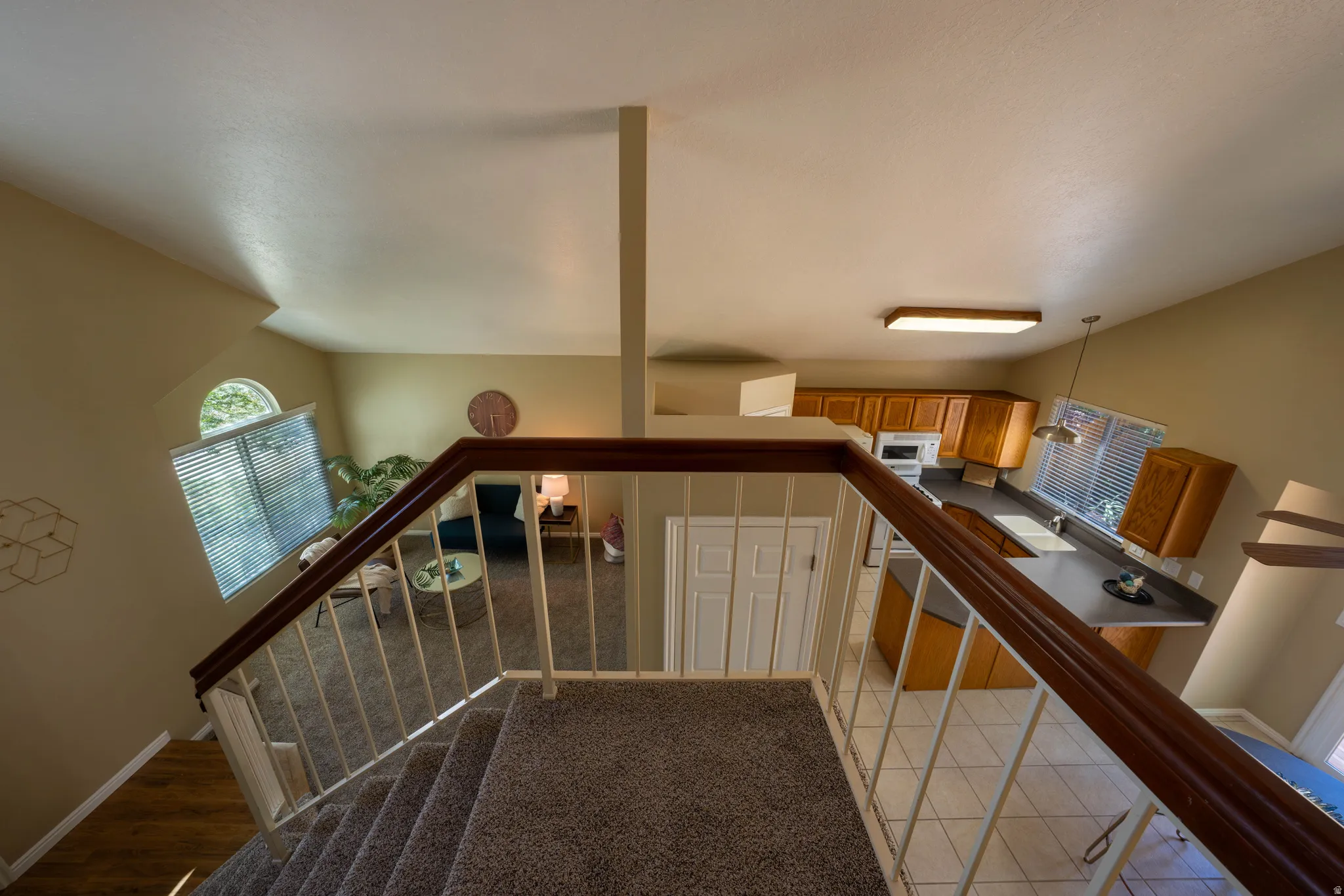 Carpeted staircase with dark wood-finish handrail and painted balusters
