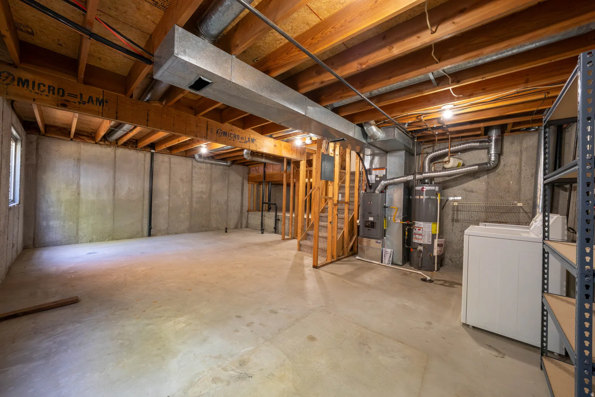 Unfinished basement with concrete flooring and exposed wood ceiling joists