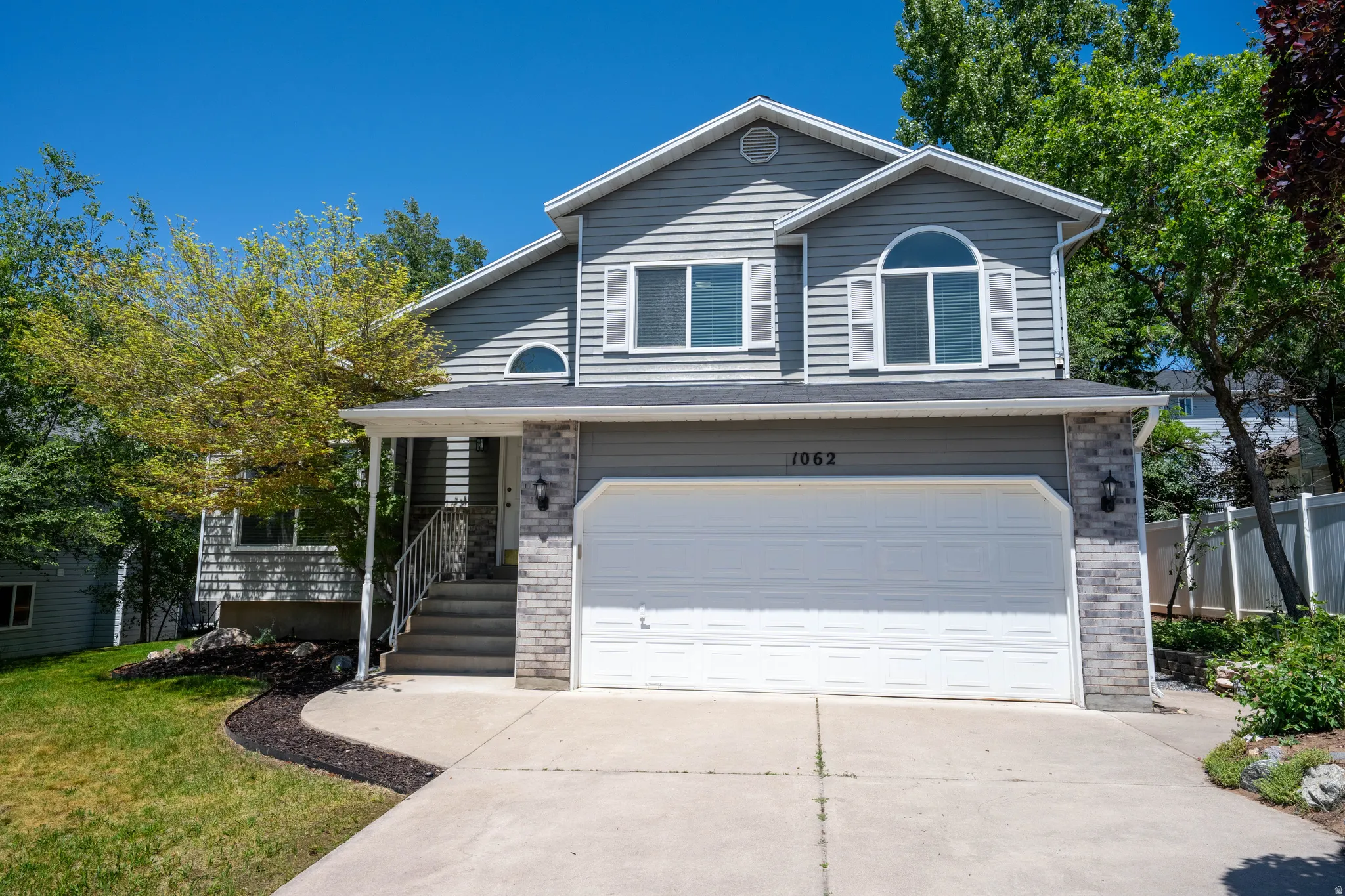 Traditional-style residence featuring gray siding, stone accent details, and a two-car garage