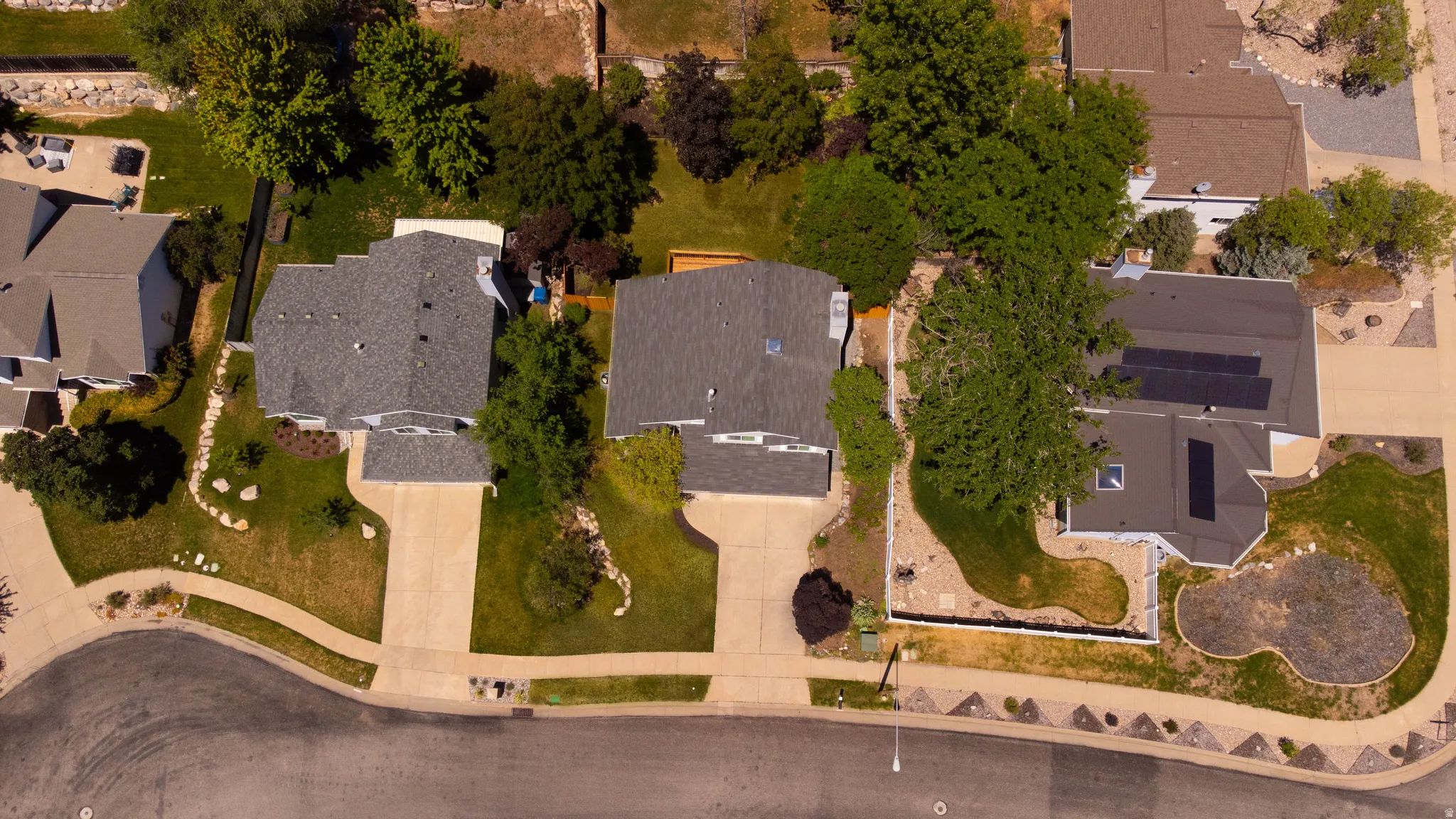 Aerial perspective showcasing three residential properties with asphalt shingle roofs