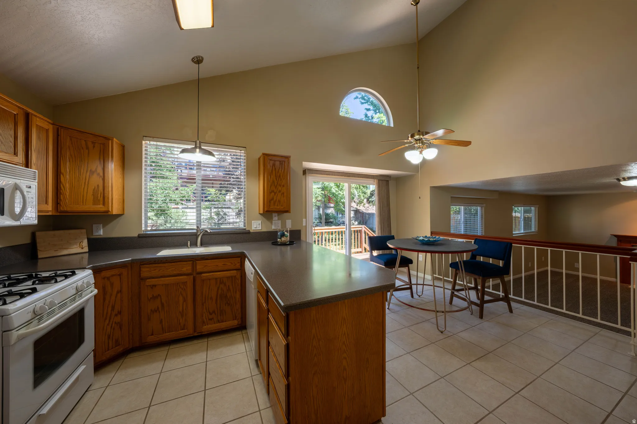 Kitchen featuring wood cabinetry, white appliances, a tile floor, and a breakfast bar