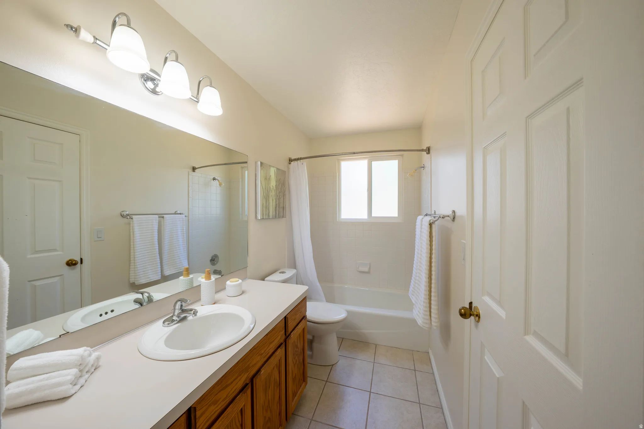 Bathroom featuring a single vanity with wood-finish cabinetry, a large wall-mounted mirror, and a three-light fixture