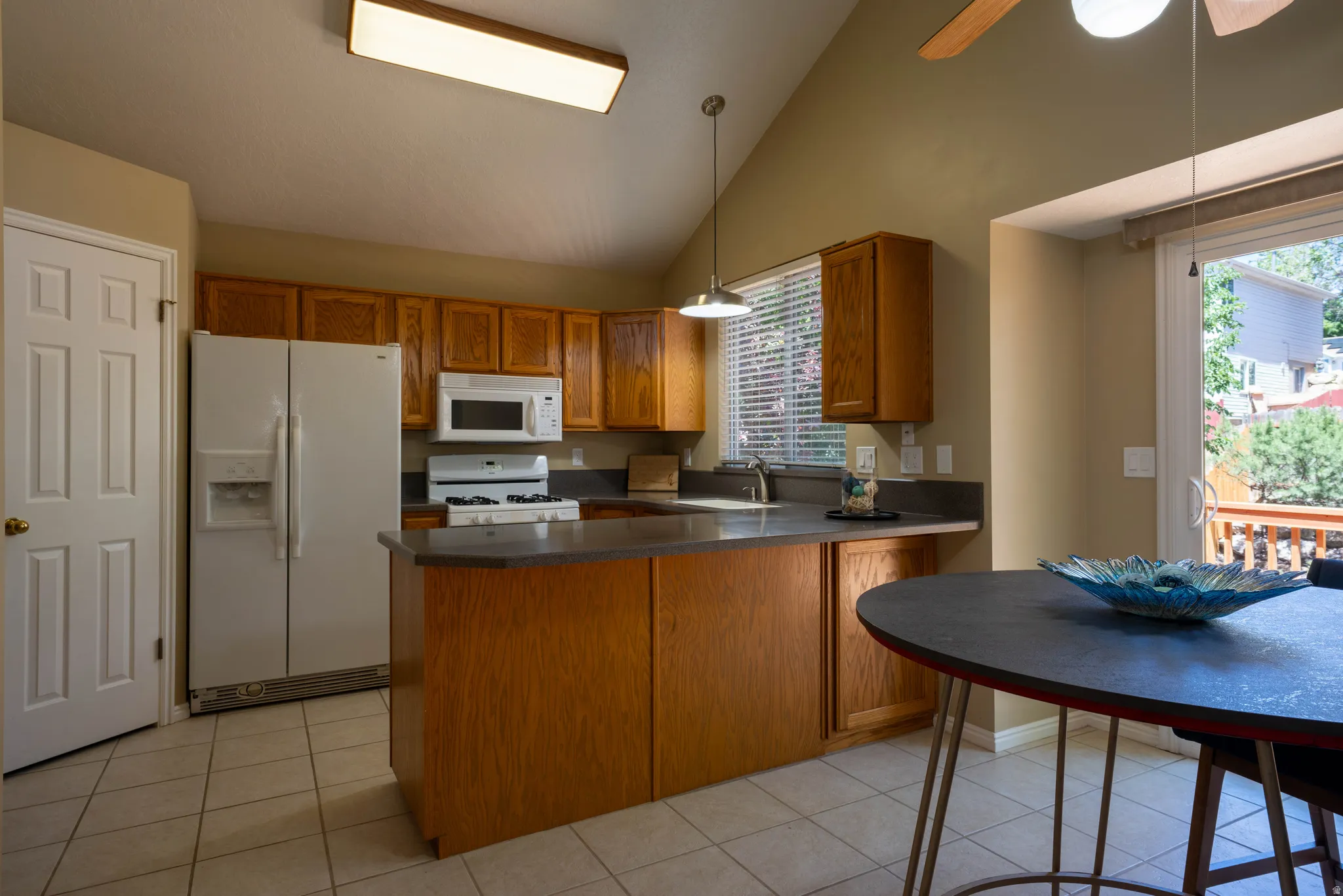 Kitchen featuring wood cabinetry, white appliances, and a central island with countertop seating