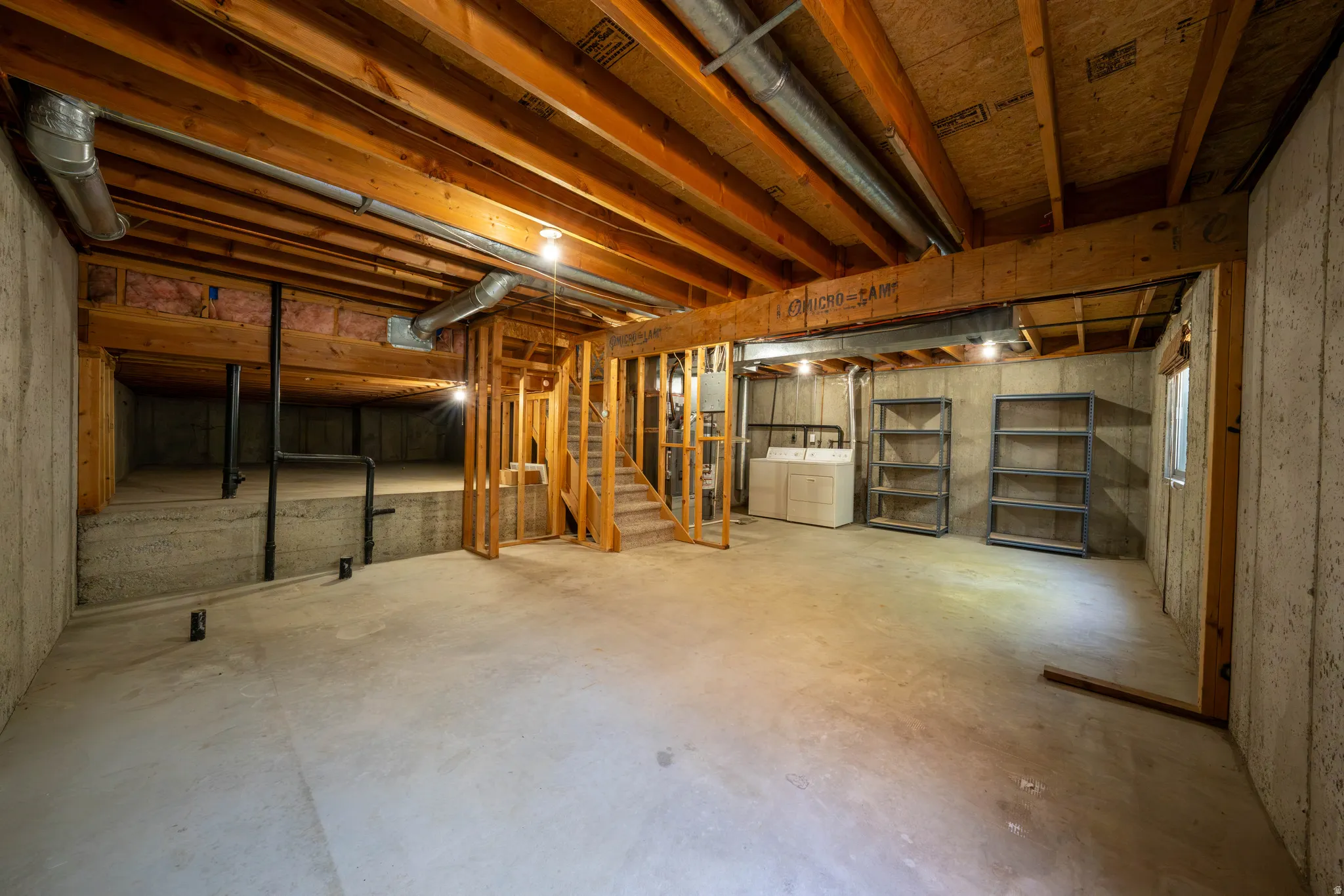 Unfinished basement with exposed wood joists and concrete flooring