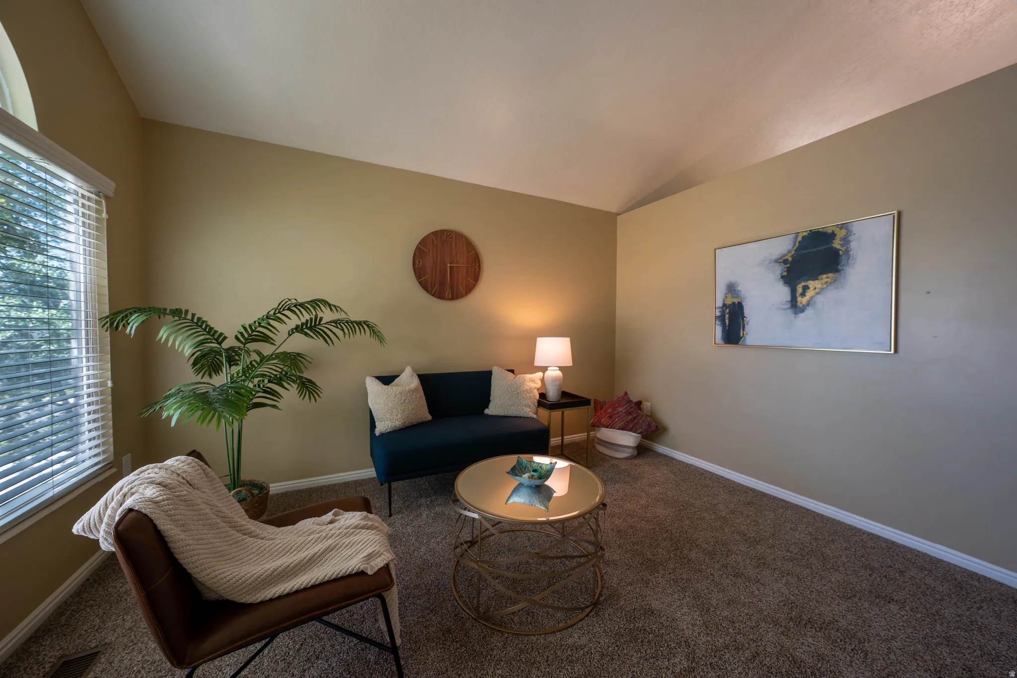 Vaulted ceiling with a large arched window, complemented by tan wall paint and brown carpet flooring