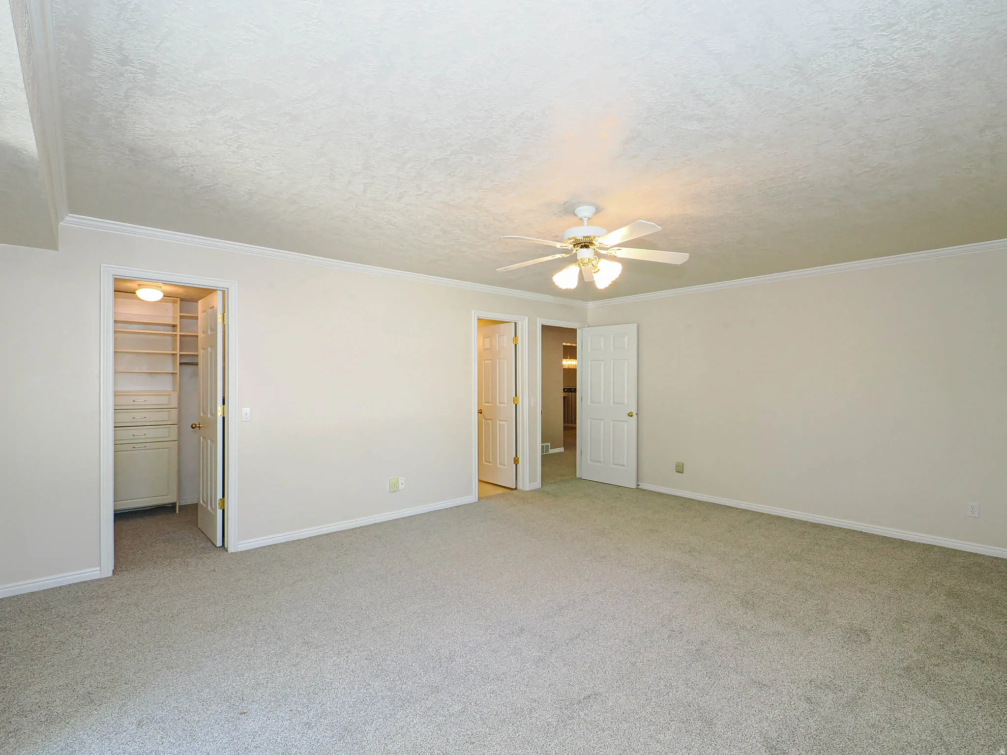 Spacious room featuring neutral carpeting, light wall paint, and white crown molding
