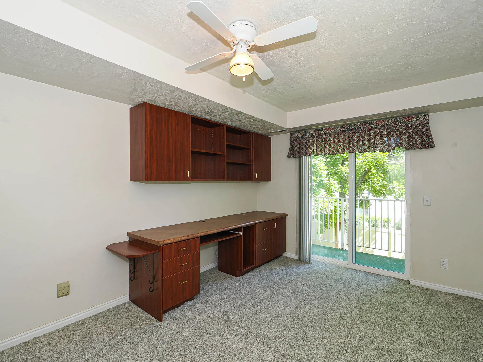 Room featuring a built-in wood-finish desk with integrated storage and overhead cabinetry