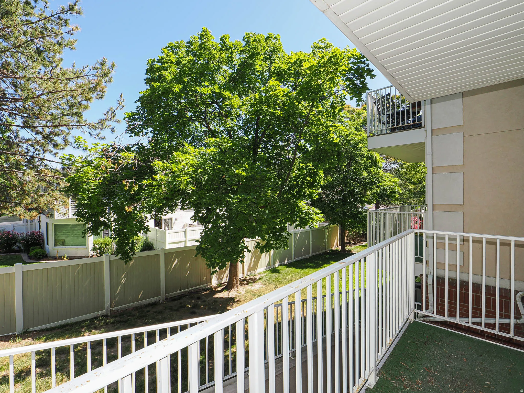 Private balcony with white metal railings, green outdoor carpeting, and a slatted white ceiling