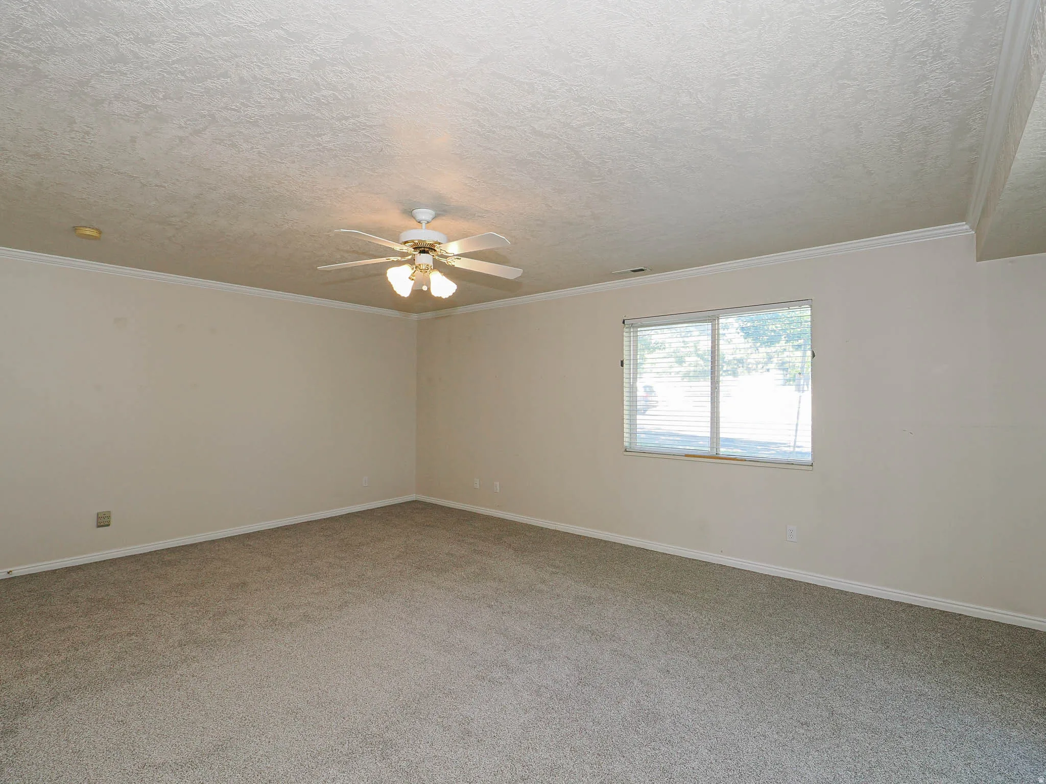 Carpeted interior space featuring a ceiling fan with integrated lighting, crown molding, a window with horizontal blinds, and a recessed light fixture