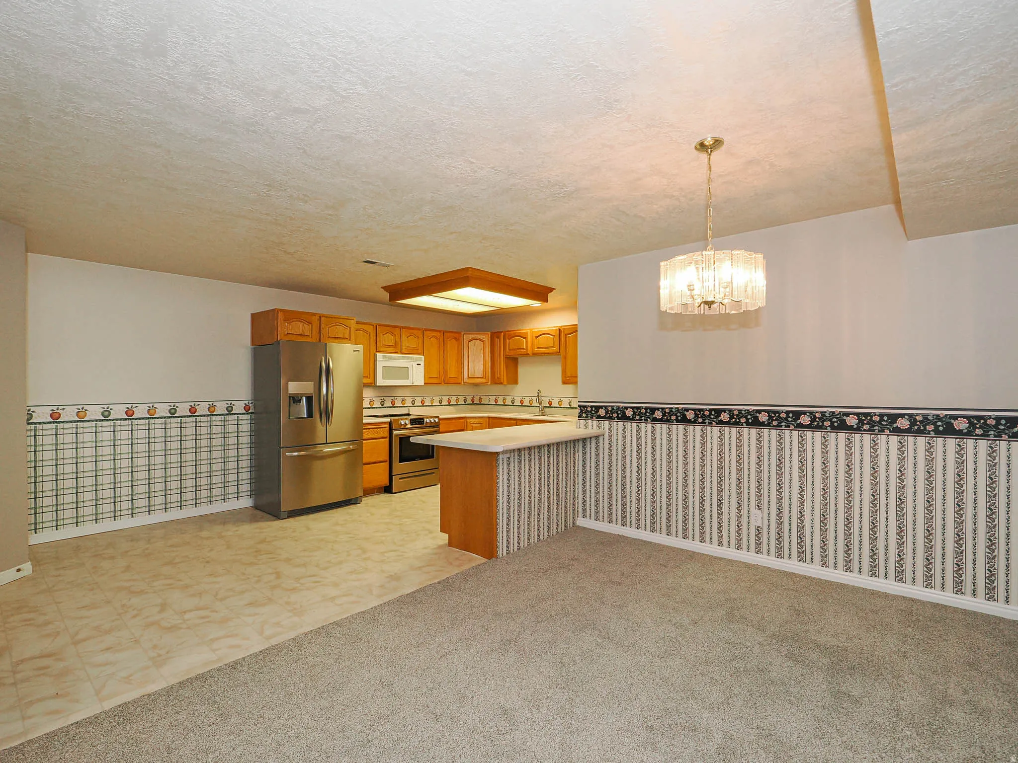 Open-concept kitchen and dining area featuring warm-toned cabinetry, stainless steel appliances, and a central island