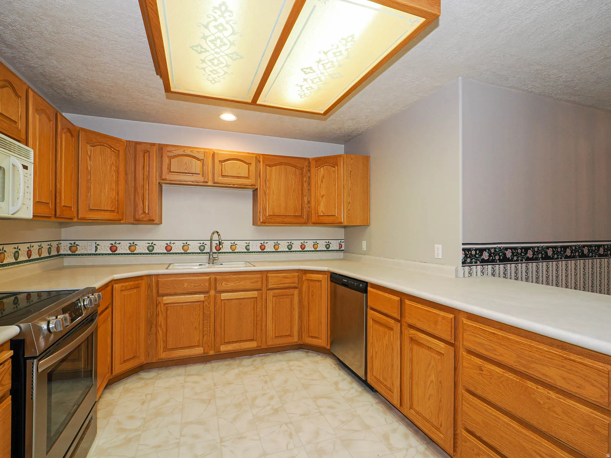 Kitchen featuring abundant wood cabinetry, an integrated stainless steel dishwasher, and a stainless steel oven