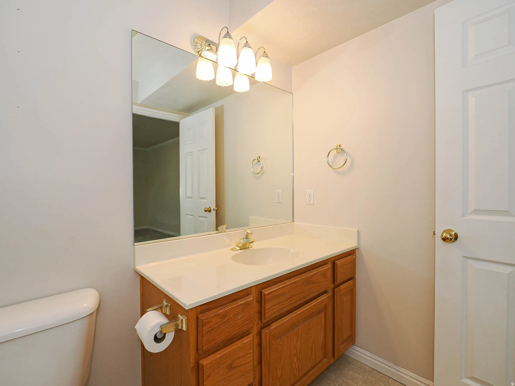 Bathroom vanity featuring a light wood-finish cabinet with a white countertop and integrated sink