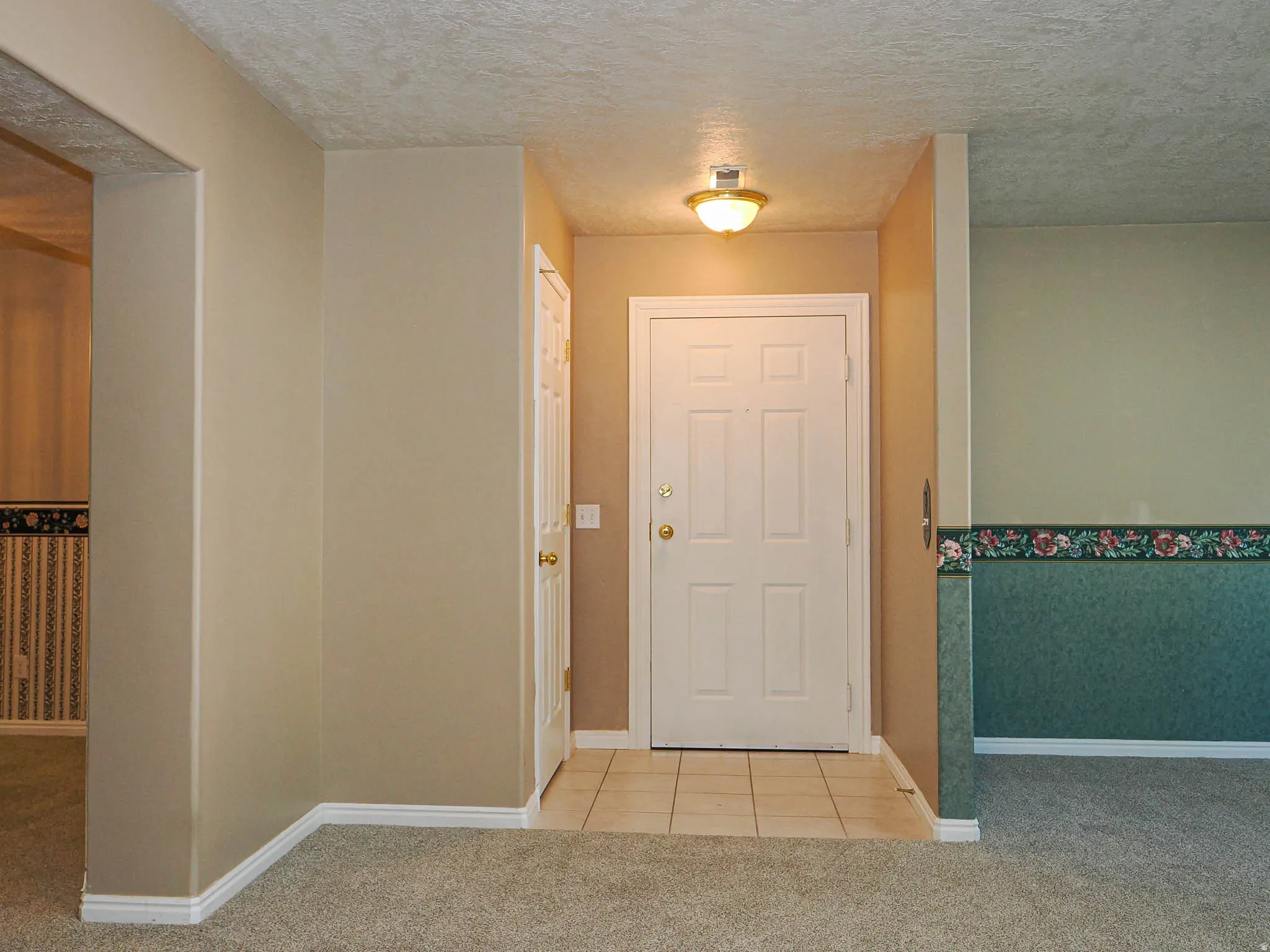 Foyer with a paneled entry door, flush mount ceiling light, and tile flooring
