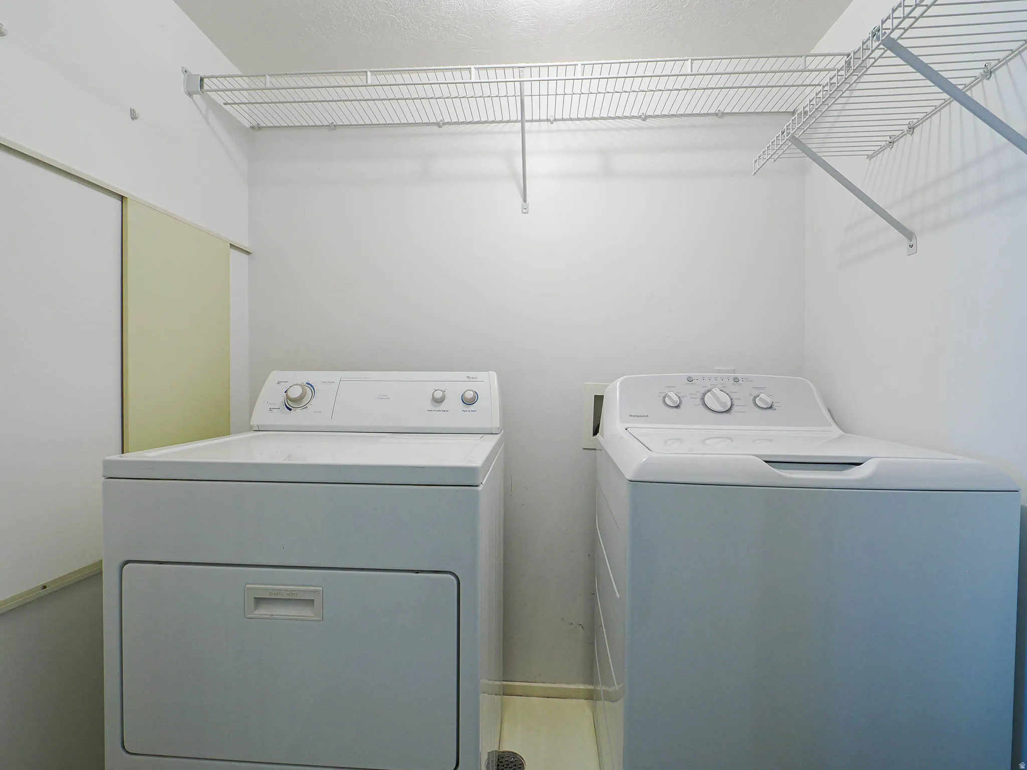 Laundry area with white wire shelving, light-toned flooring, and neutral wall finishes
