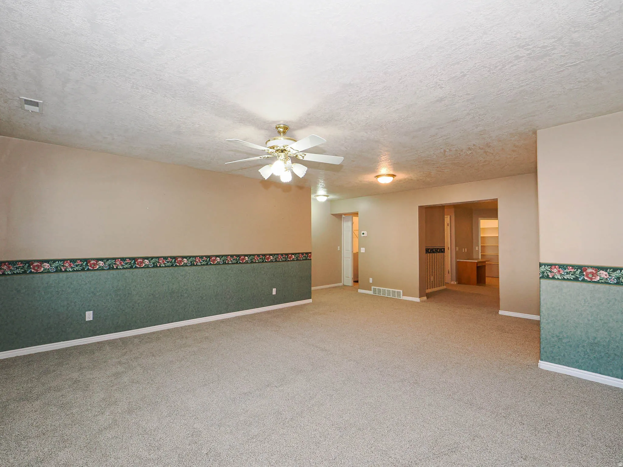 Spacious interior with neutral carpeting and a ceiling fan light fixture