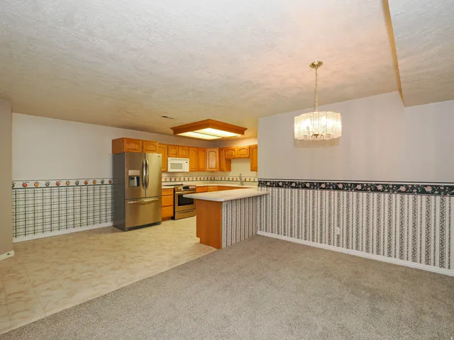 Open-concept kitchen and dining area featuring warm-toned cabinetry, stainless steel appliances, and a central island
