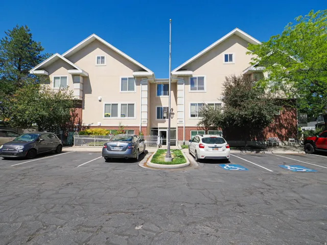 Multi-story building featuring a stucco exterior with brick accents and pitched roofs