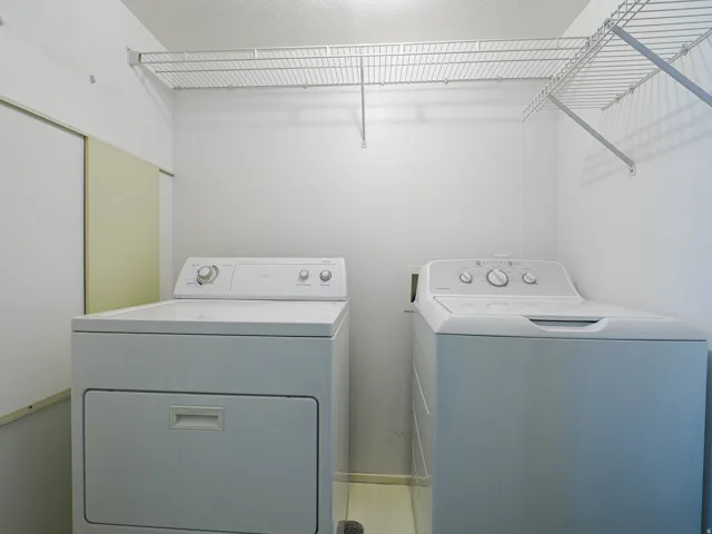 Laundry area with white wire shelving, light-toned flooring, and neutral wall finishes