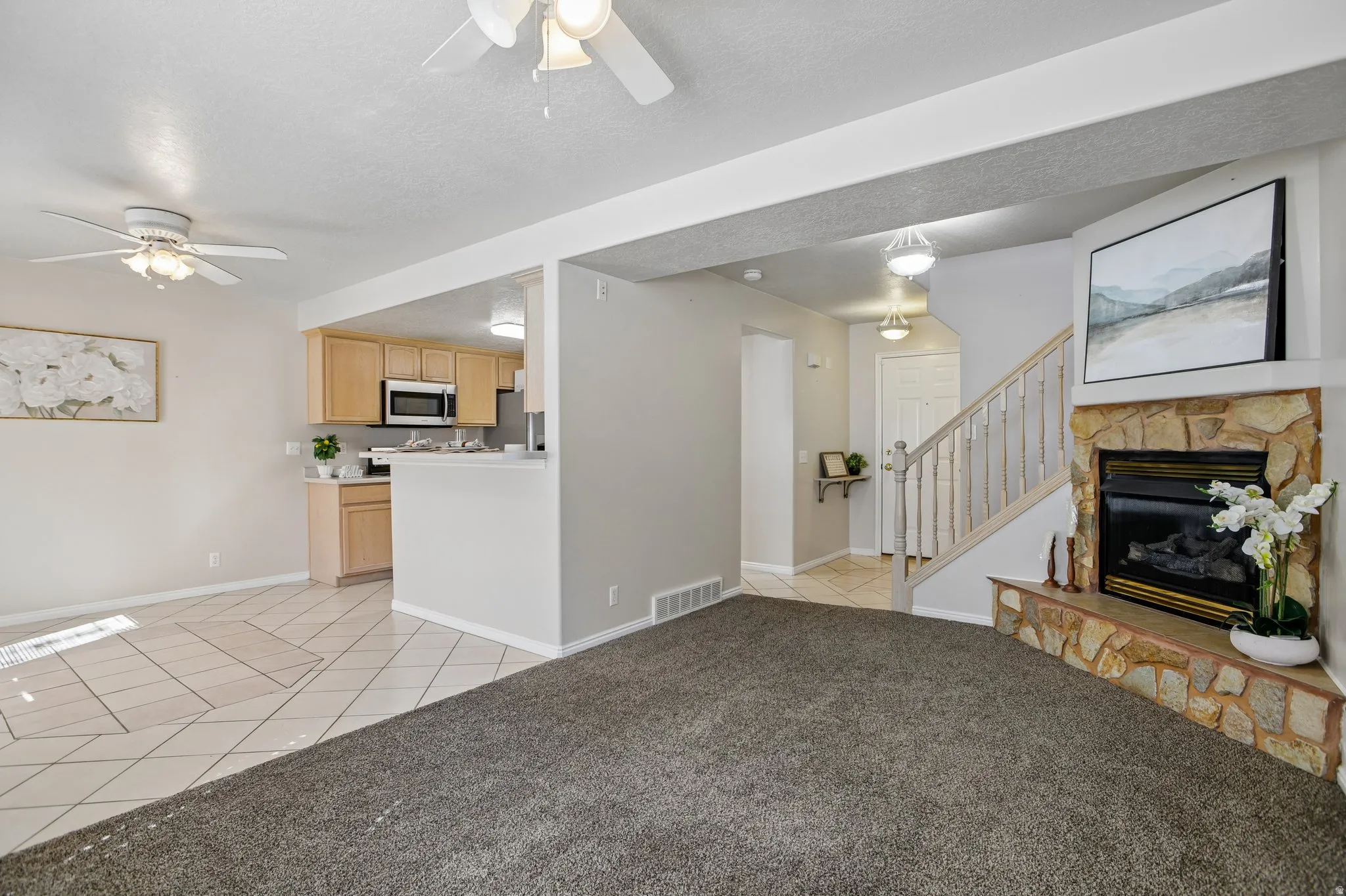 Living area featuring a stone-clad fireplace and carpet flooring
