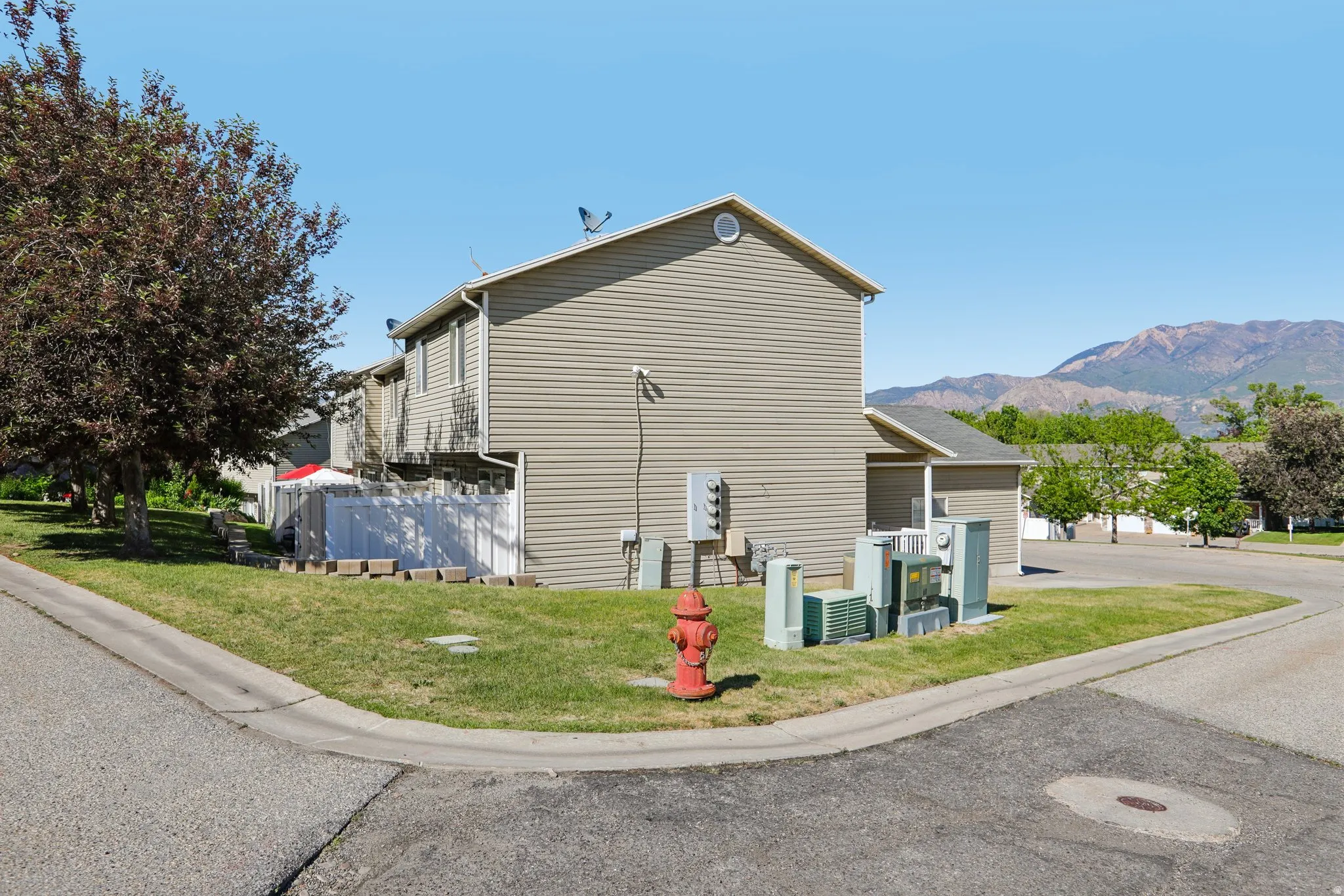 Exterior siding property featuring a white privacy fence and a paved roadway