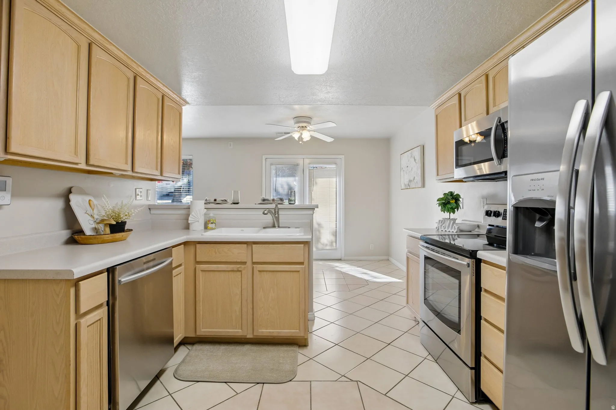 Kitchen featuring light wood cabinetry, light-toned countertops, and stainless steel appliances