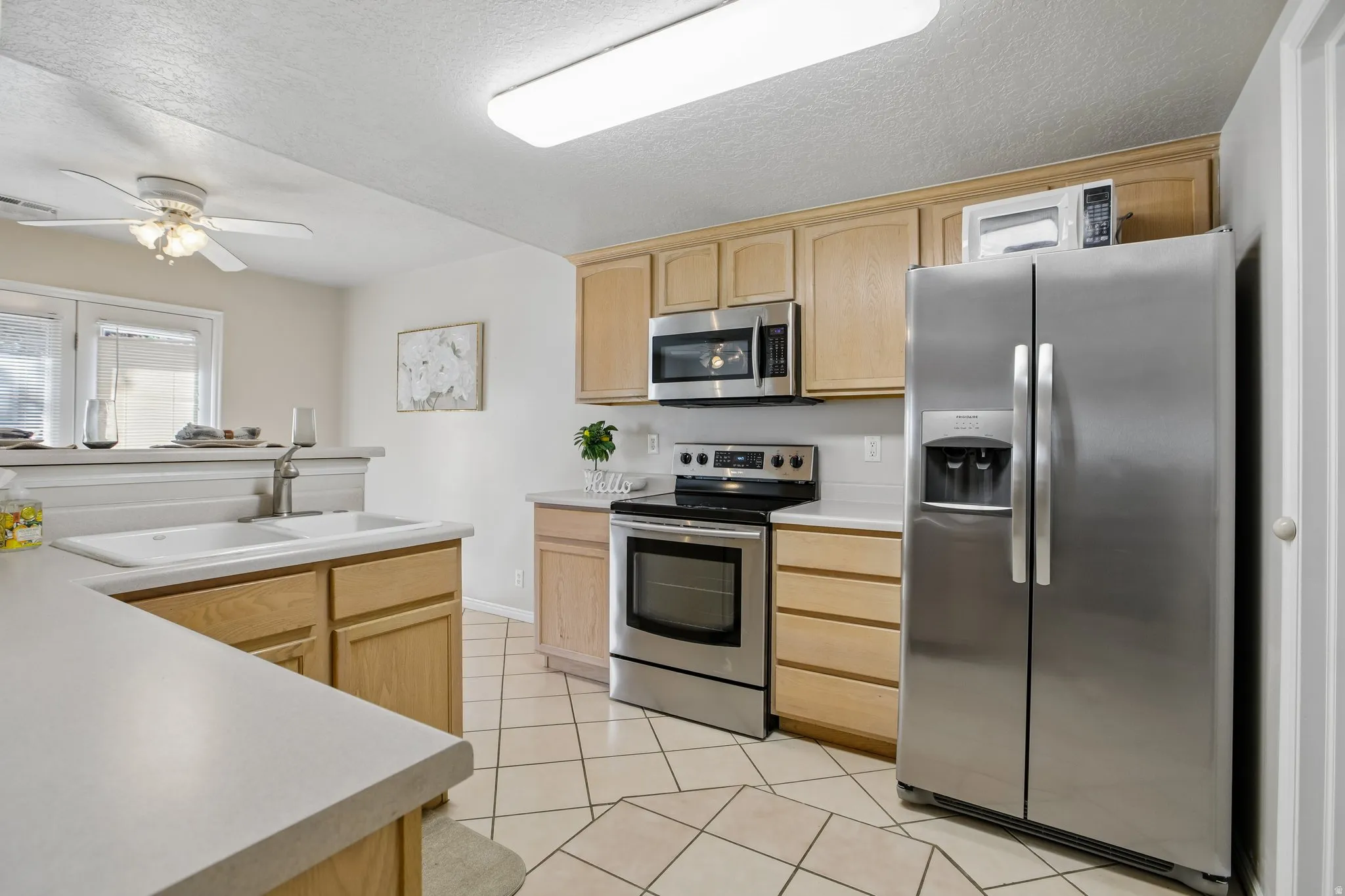 Kitchen featuring a double basin sink, light-toned cabinetry, stainless steel appliances, and tile flooring
