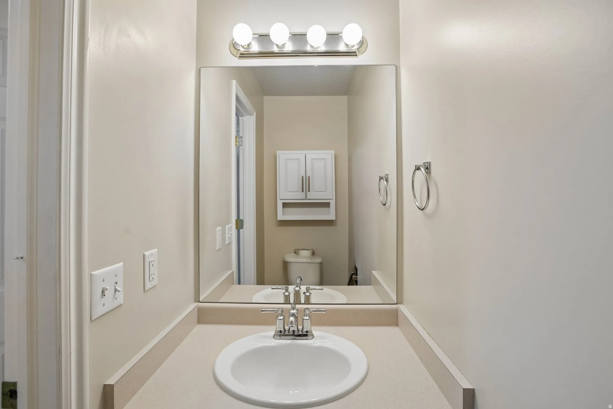 Bathroom vanity with an integrated sink, polished chrome faucet, and a large wall-mounted mirror