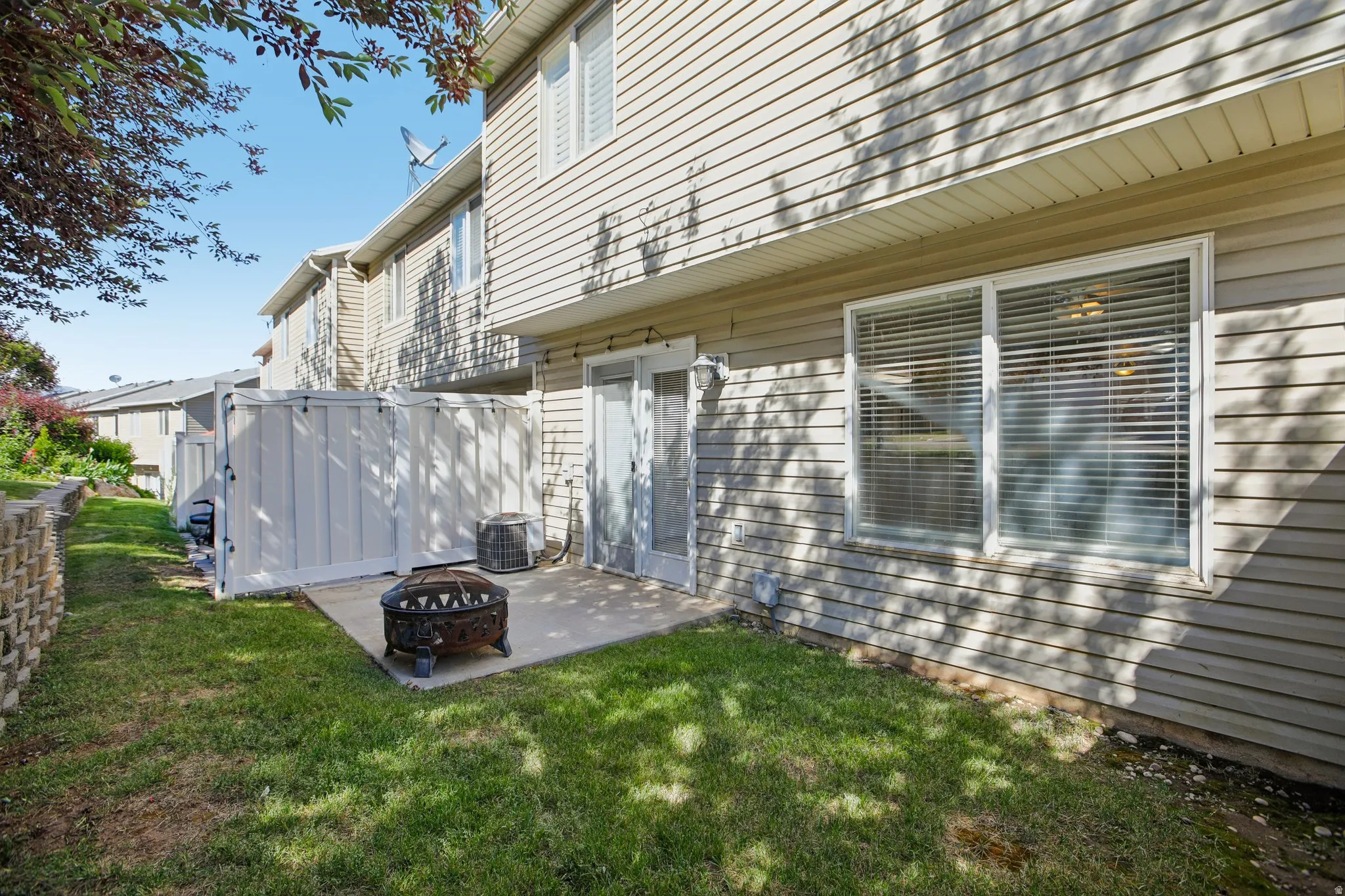Private concrete patio area featuring a white privacy fence and a grassy yard
