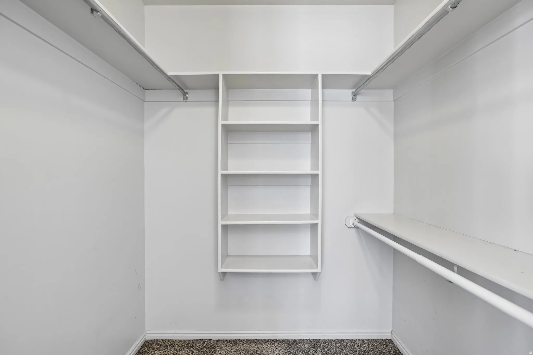 Walk-in closet featuring built-in shelving, multiple hanging rods, and neutral-toned carpeting