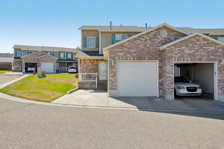 Townhome exterior featuring brick and siding finishes, an integrated single-car garage, and a concrete driveway