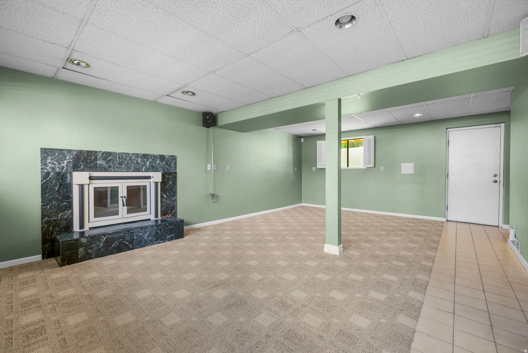 Spacious room featuring a prominent fireplace with a dark, veined stone surround and hearth