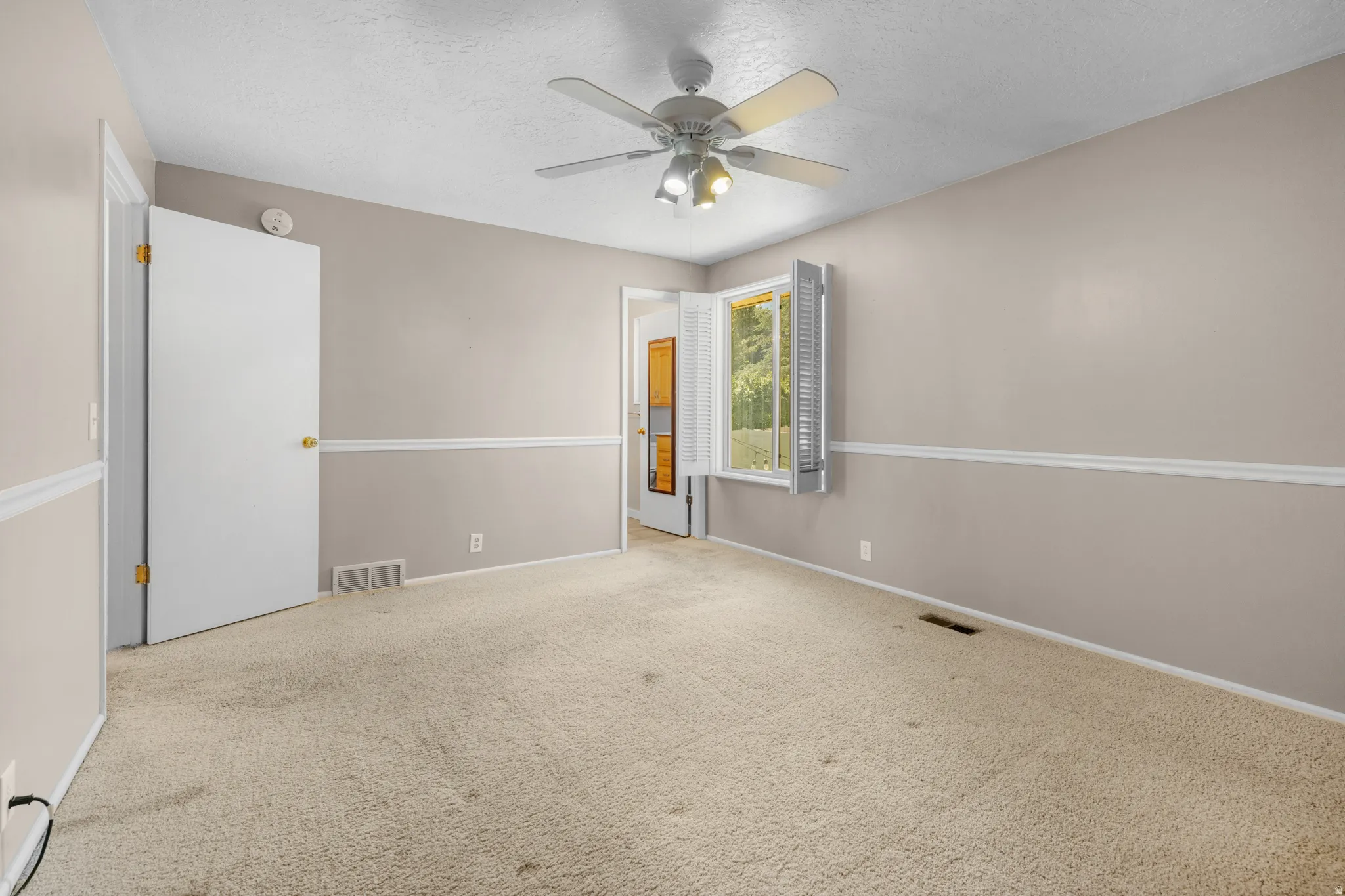 Neutral-toned room featuring carpeted flooring and a ceiling fan with integrated lighting