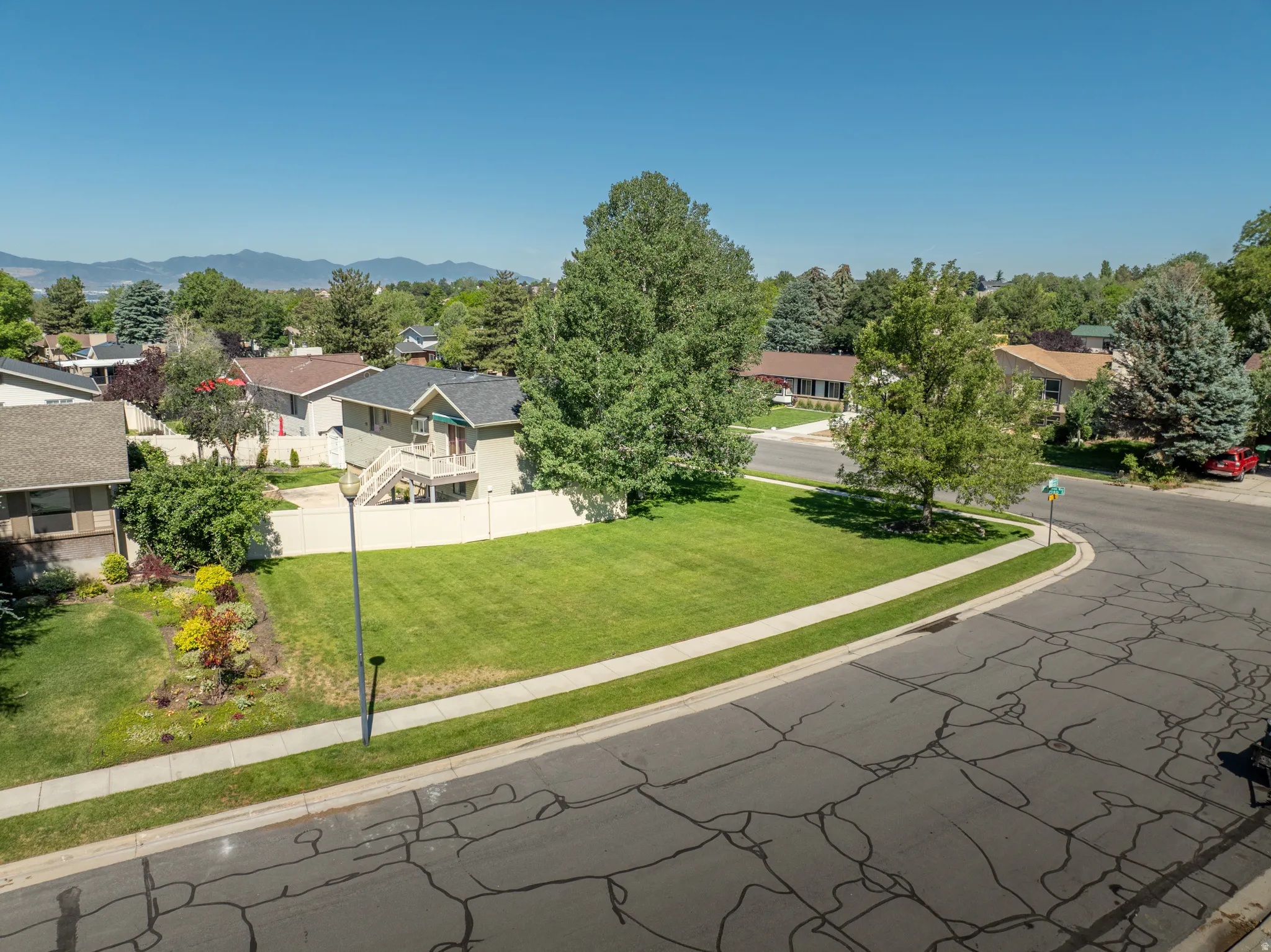 Expansive corner lot featuring a manicured lawn, established trees, and mature landscaping