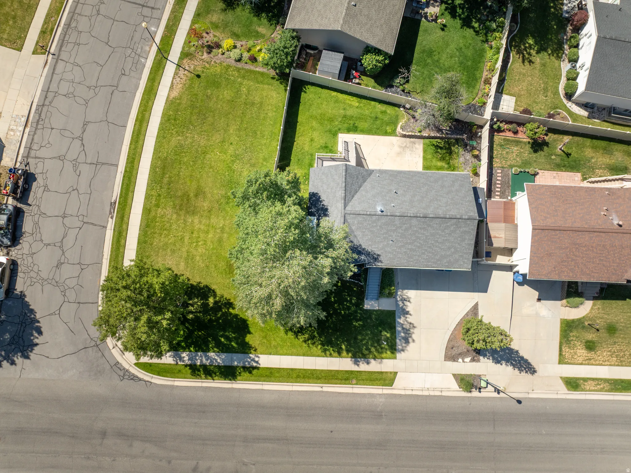 Property situated on a corner lot featuring a spacious front lawn, mature trees, and a paved driveway