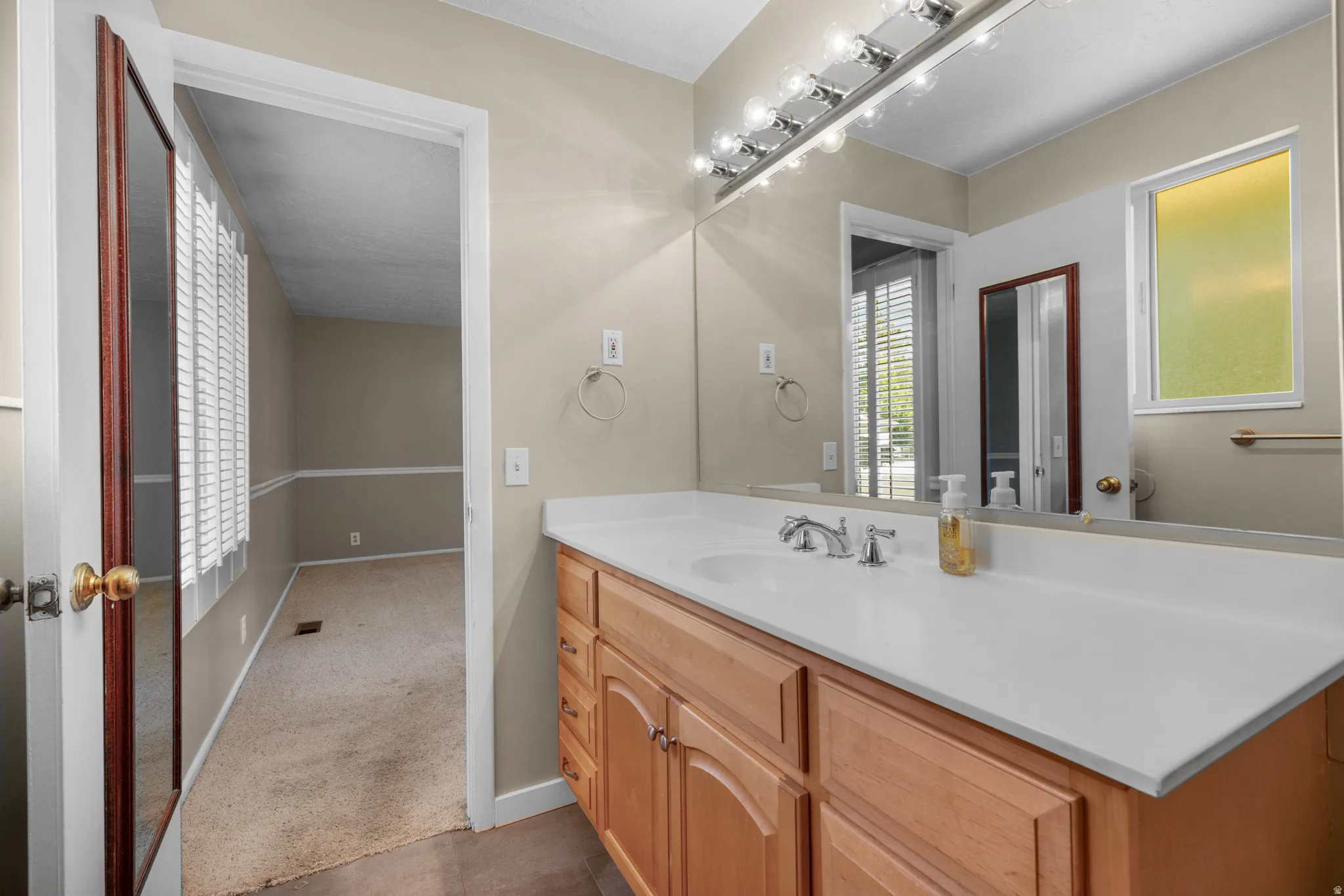 Bathroom vanity featuring a single sink, chrome faucet, and expansive countertop