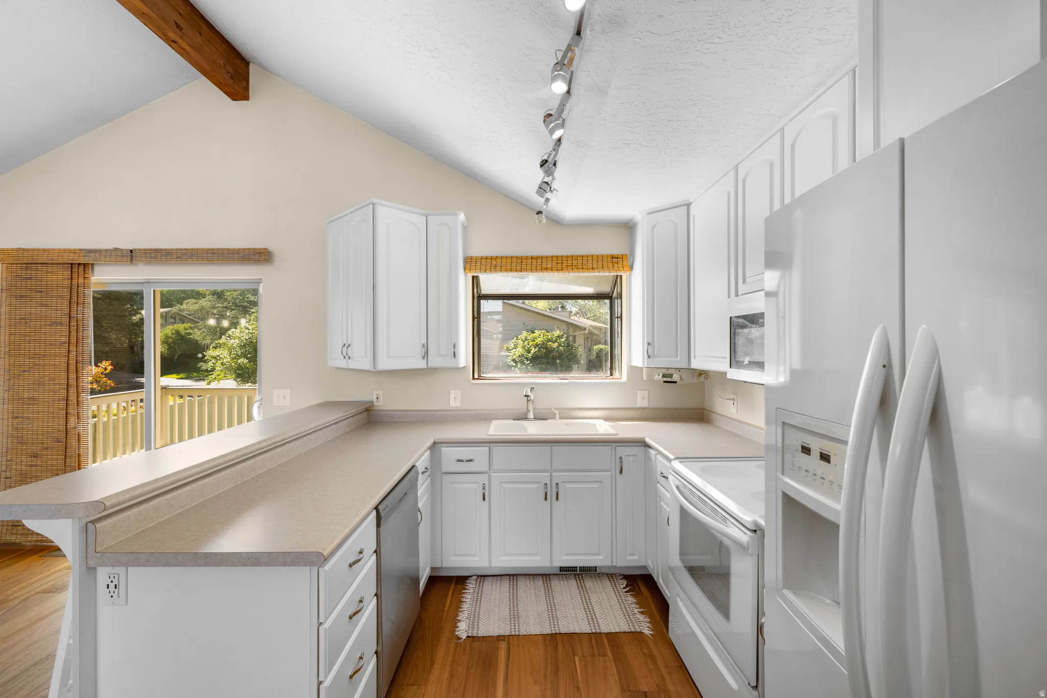 Bright kitchen featuring white cabinetry, light-toned countertops, and integrated appliances
