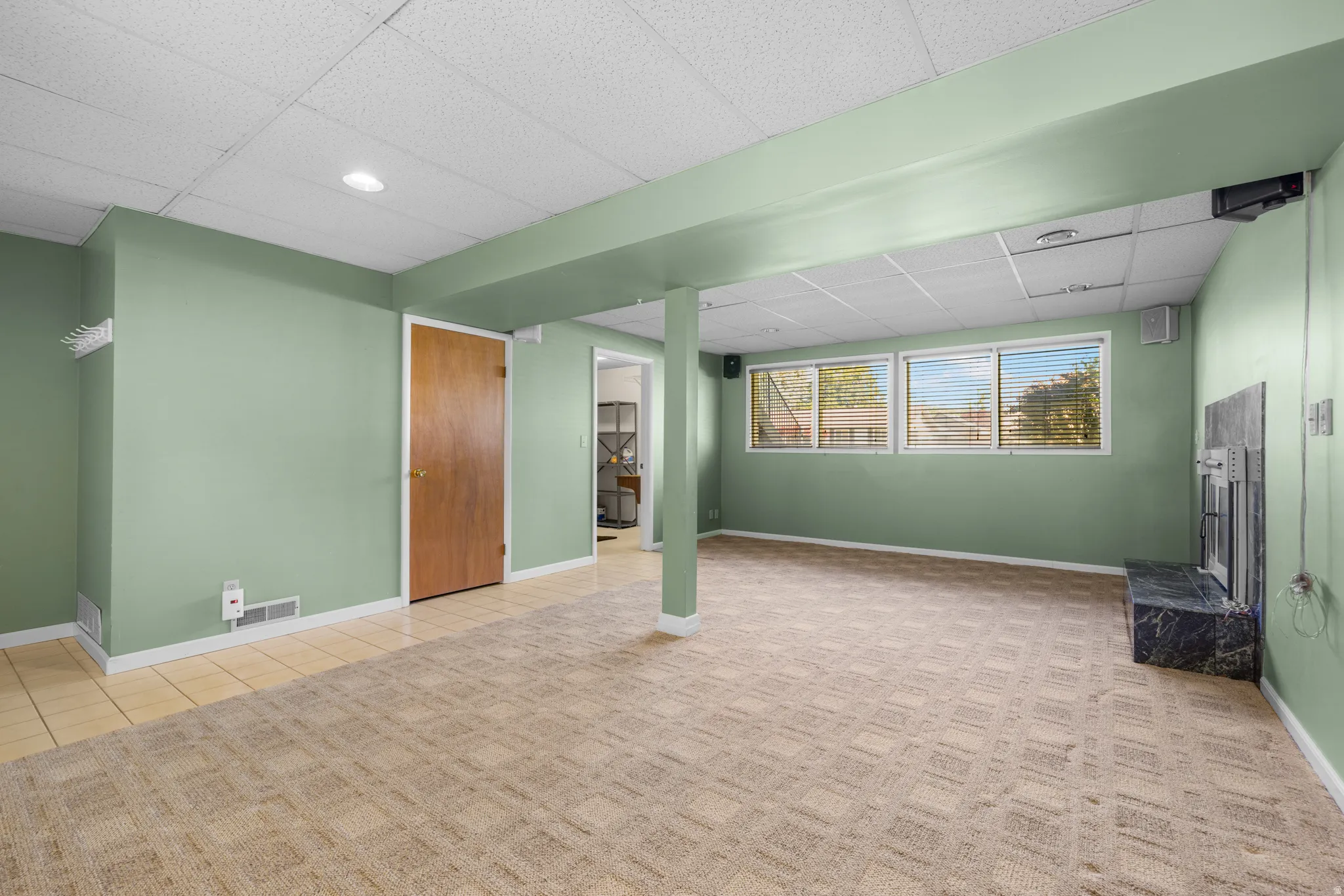 Spacious room featuring patterned carpet, light green walls, a black stone fireplace, and multiple windows