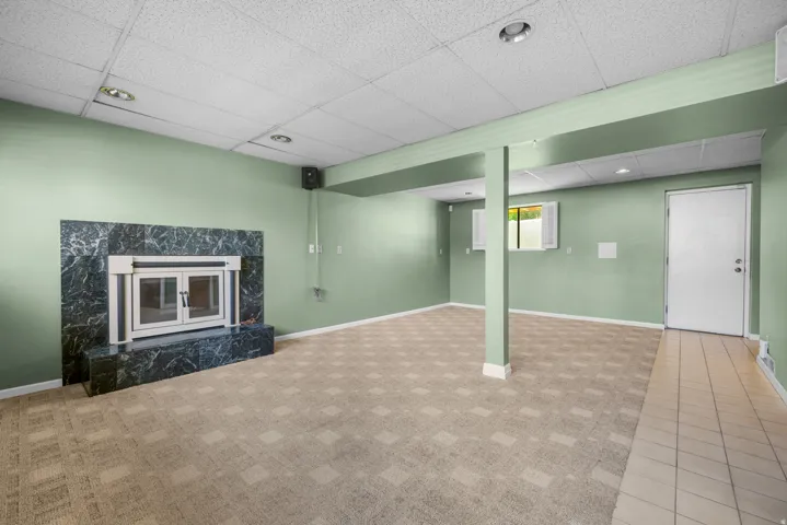 Spacious room featuring a prominent fireplace with a dark, veined stone surround and hearth