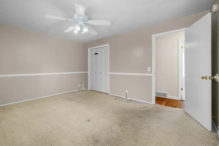 Carpeted room featuring a ceiling fan with integrated lighting, bi-fold closet doors, wall molding, and a neutral color palette