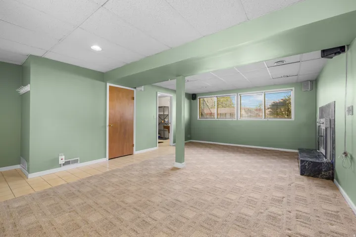 Spacious room featuring patterned carpet, light green walls, a black stone fireplace, and multiple windows