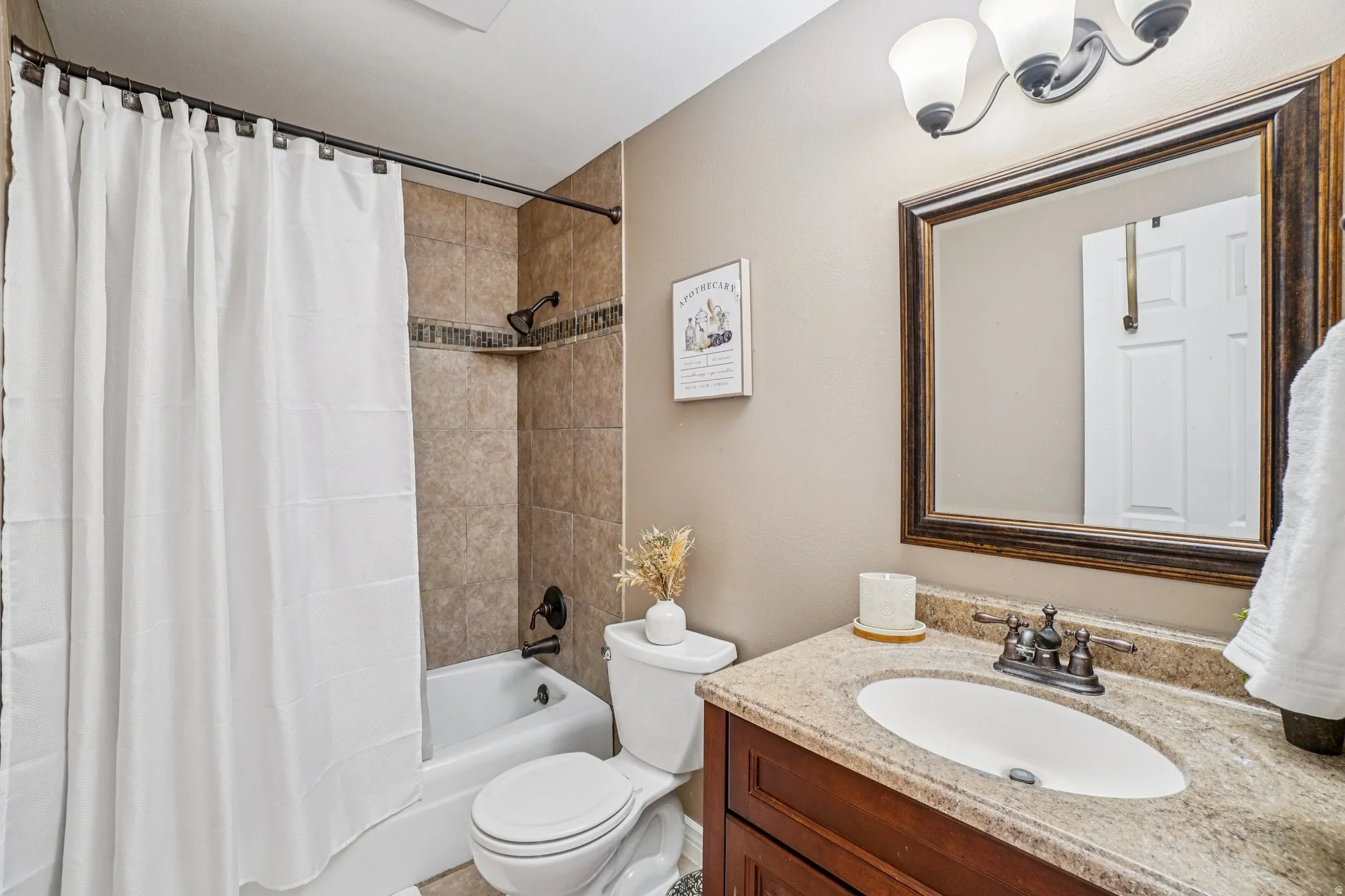 Bathroom vanity with an oval undermount sink, granite countertop, and dark wood-finish cabinetry