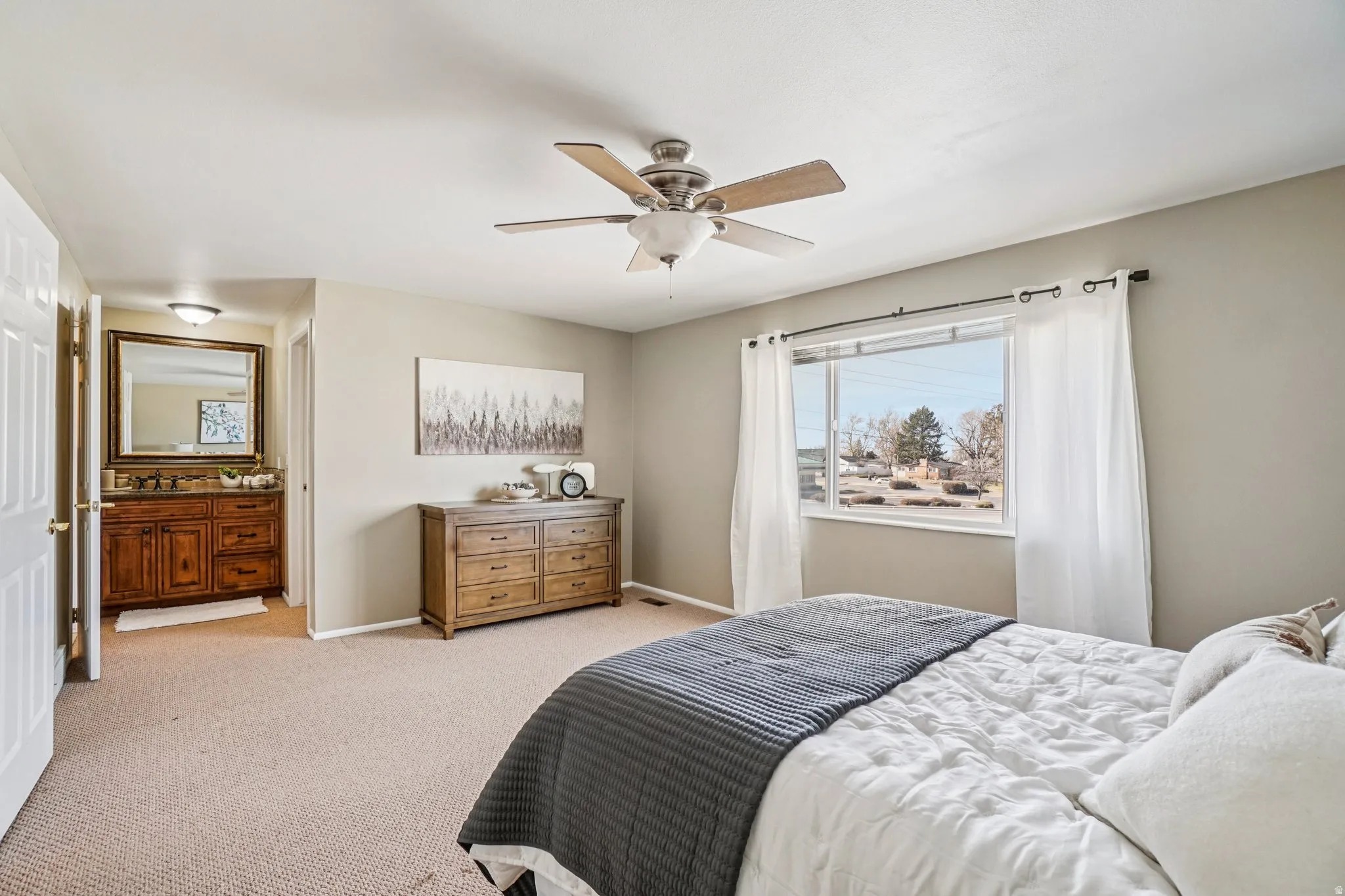 Bedroom featuring a ceiling fan with light fixture, large window, and carpet flooring
